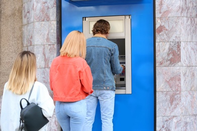 Photo of People standing in queue to cash machine outdoors