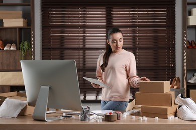 Photo of Shoes seller working with tablet in office. Online store