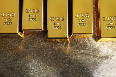 Photo of Many gold bars on shiny fabric, flat lay. Space for text