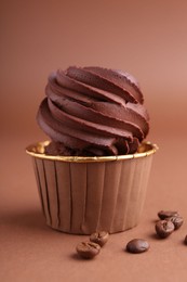 Photo of Delicious chocolate cupcake and coffee beans on brown background, closeup