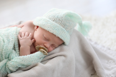 Photo of Cute newborn baby in warm hat sleeping on plaid