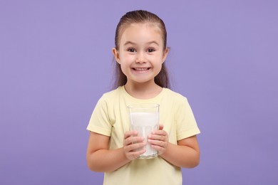 Photo of Cute girl with glass of fresh milk on violet background