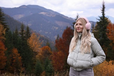 Photo of Young beautiful woman wearing warm earmuffs in mountains