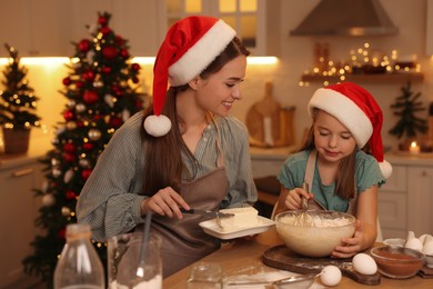 Photo of Mother with her cute little daughter making dough for Christmas cookies in kitchen