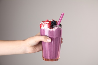 Photo of Woman with tasty milk shake on grey background, closeup