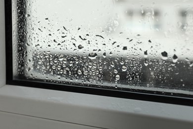 Photo of Window glass with drops of condensate indoors, closeup