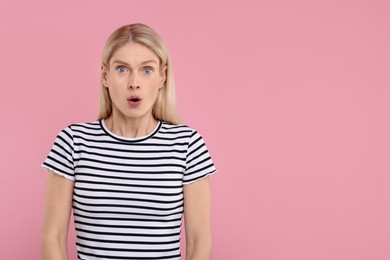 Photo of Portrait of surprised woman on pink background, space for text