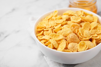 Photo of Breakfast cereal. Tasty crispy corn flakes in bowl on white marble table, closeup. Space for text