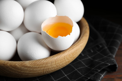 Photo of Many fresh raw chicken eggs in bowl on table, closeup