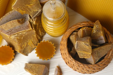 Photo of Different natural beeswax blocks and jar of honey on white wooden table, above view