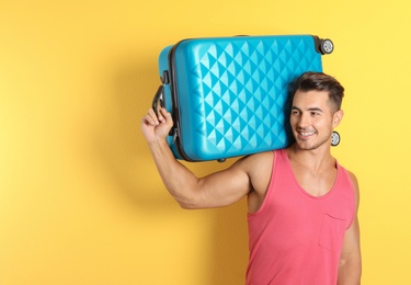 Photo of Young man with suitcase on color background