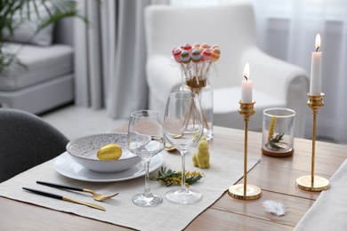 Photo of Beautiful Easter table setting with burning candles and floral decor indoors