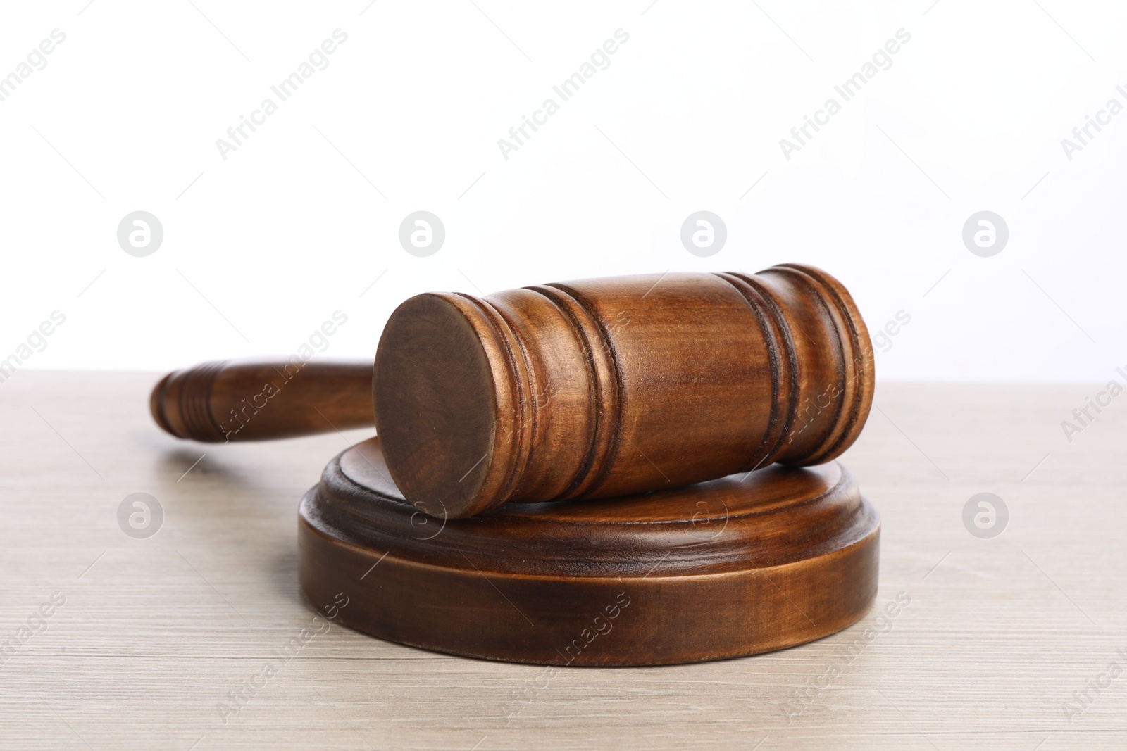 Photo of Wooden gavel on light table against white background