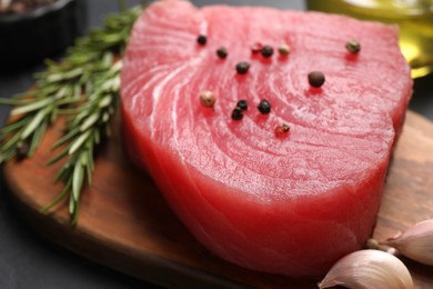 Photo of Raw tuna fillet with spices on wooden board, closeup