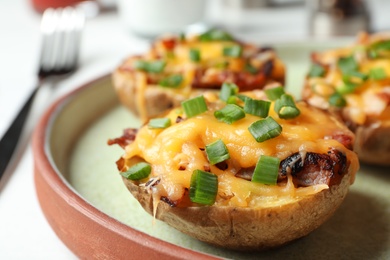 Photo of Plate of baked potatoes with cheese and bacon on table, closeup