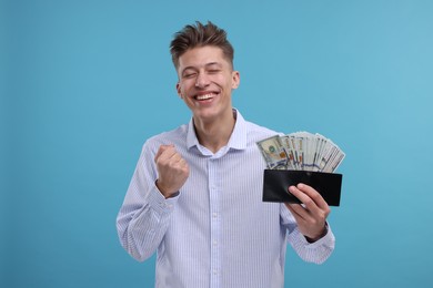 Photo of Happy man with wallet and money on light blue background