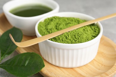 Photo of Green matcha powder and bamboo scoop on table, closeup