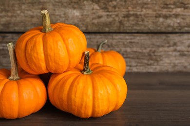 Photo of Fresh ripe pumpkins on wooden table, space for text