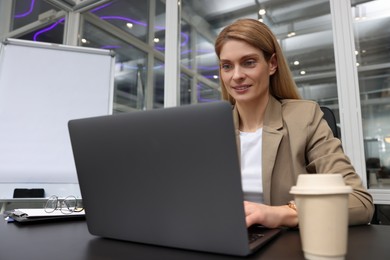 Photo of Woman working on laptop at black desk in office