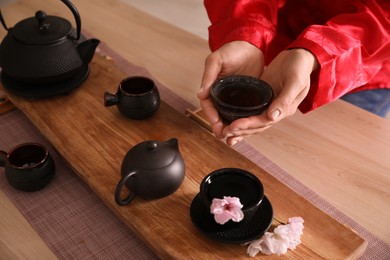 Photo of Guest holding cup of freshly brewed tea during traditional ceremony at table, closeup