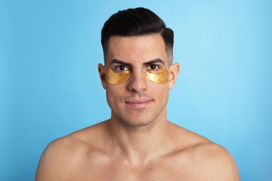 Photo of Man with golden under eye patches on light blue background