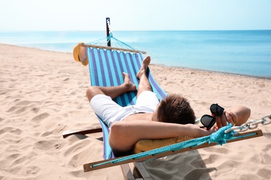 Photo of Young man relaxing in hammock on beach