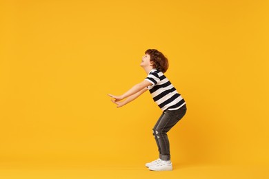 Photo of Happy little boy dancing on yellow background. Space for text