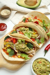Photo of Delicious tacos with guacamole, meat and vegetables on white wooden table