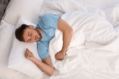 Photo of Young handsome man sleeping in bed at home, above view. Early morning