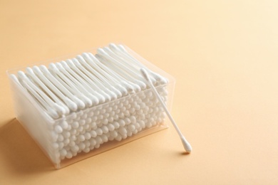 Photo of Plastic container with cotton swabs on color background. Space for text
