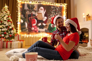 Image of Couple watching movie on projection screen in room decorated for Christmas