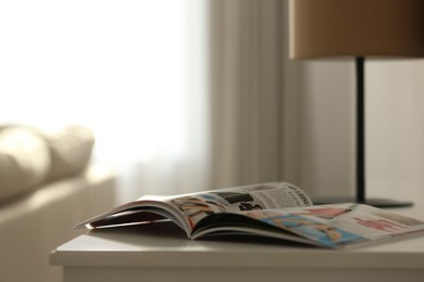 Photo of Fashion magazine on white table in living room, space for text