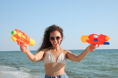Photo of African American woman with water guns having fun on beach