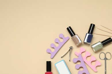 Photo of Nail polishes and set of pedicure tools on beige background, flat lay. Space for text