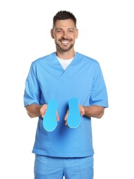 Photo of Handsome male orthopedist showing insoles on white background