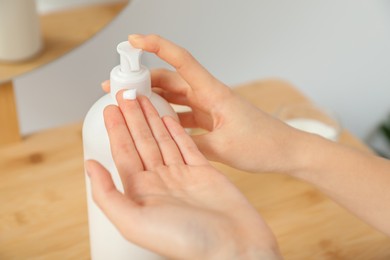 Photo of Woman applying body cream on hand in room, closeup