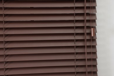 Photo of Stylish horizontal window blinds on white wall, closeup