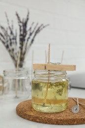 Photo of Glass jar with melted wax on white table. Handmade candle