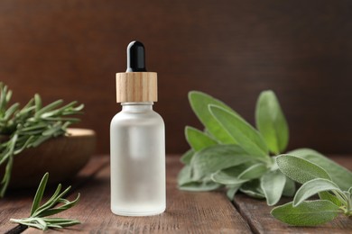 Photo of Bottle of essential oil and fresh herbs on wooden table, space for text