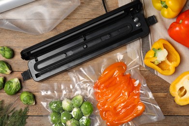 Photo of Vacuum packing sealer and different food products on wooden table, flat lay