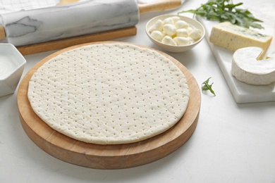 Photo of Pizza crust and fresh ingredients on white table