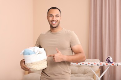 Photo of Happy man with basket full of laundry at home