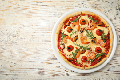 Photo of Delicious seafood pizza on white wooden table, top view. Space for text