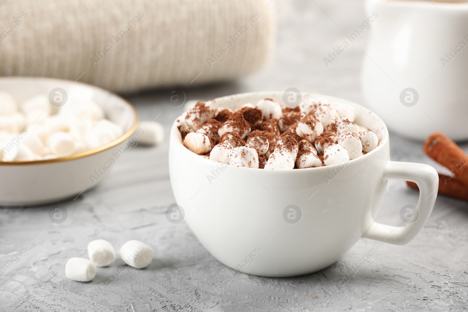 Photo of Cup of aromatic hot chocolate with marshmallows and cocoa powder on gray table, closeup