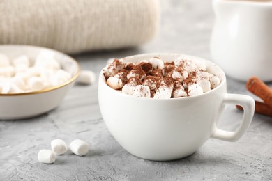 Photo of Cup of aromatic hot chocolate with marshmallows and cocoa powder on gray table, closeup