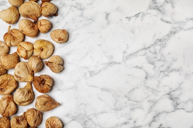 Photo of Dried figs on marble table, top view with space for text. Healthy fruit