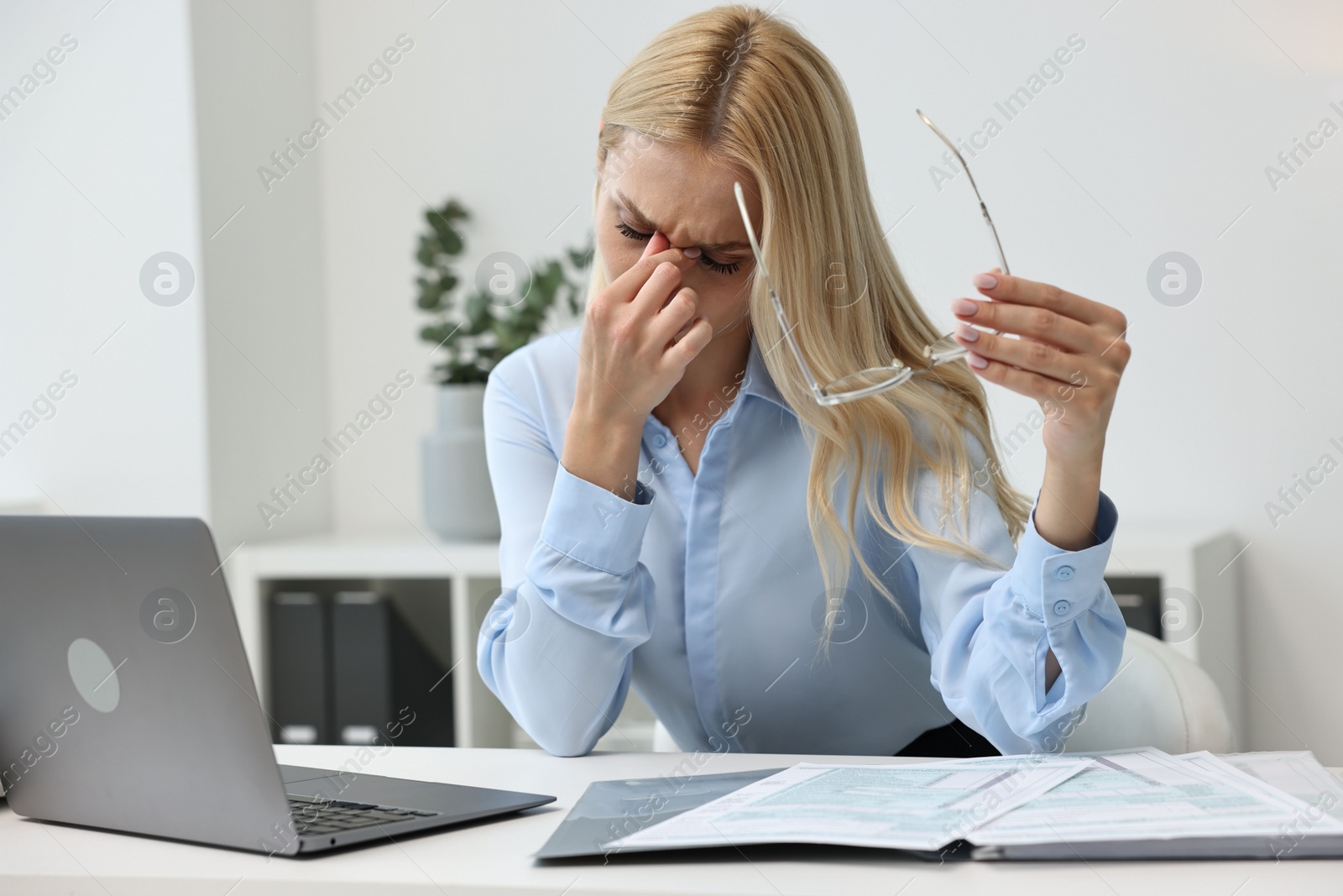 Photo of Overwhelmed woman with glasses at table in office