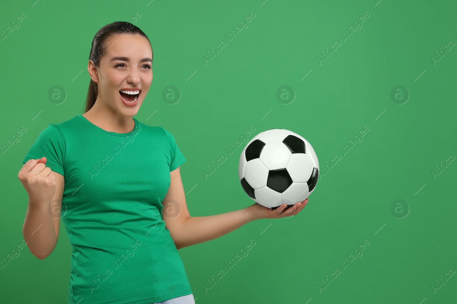 Photo of Happy fan with soccer ball celebrating on green background, space for text