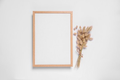 Photo of Empty photo frame and dry decorative spikes on white background, top view. Space for design