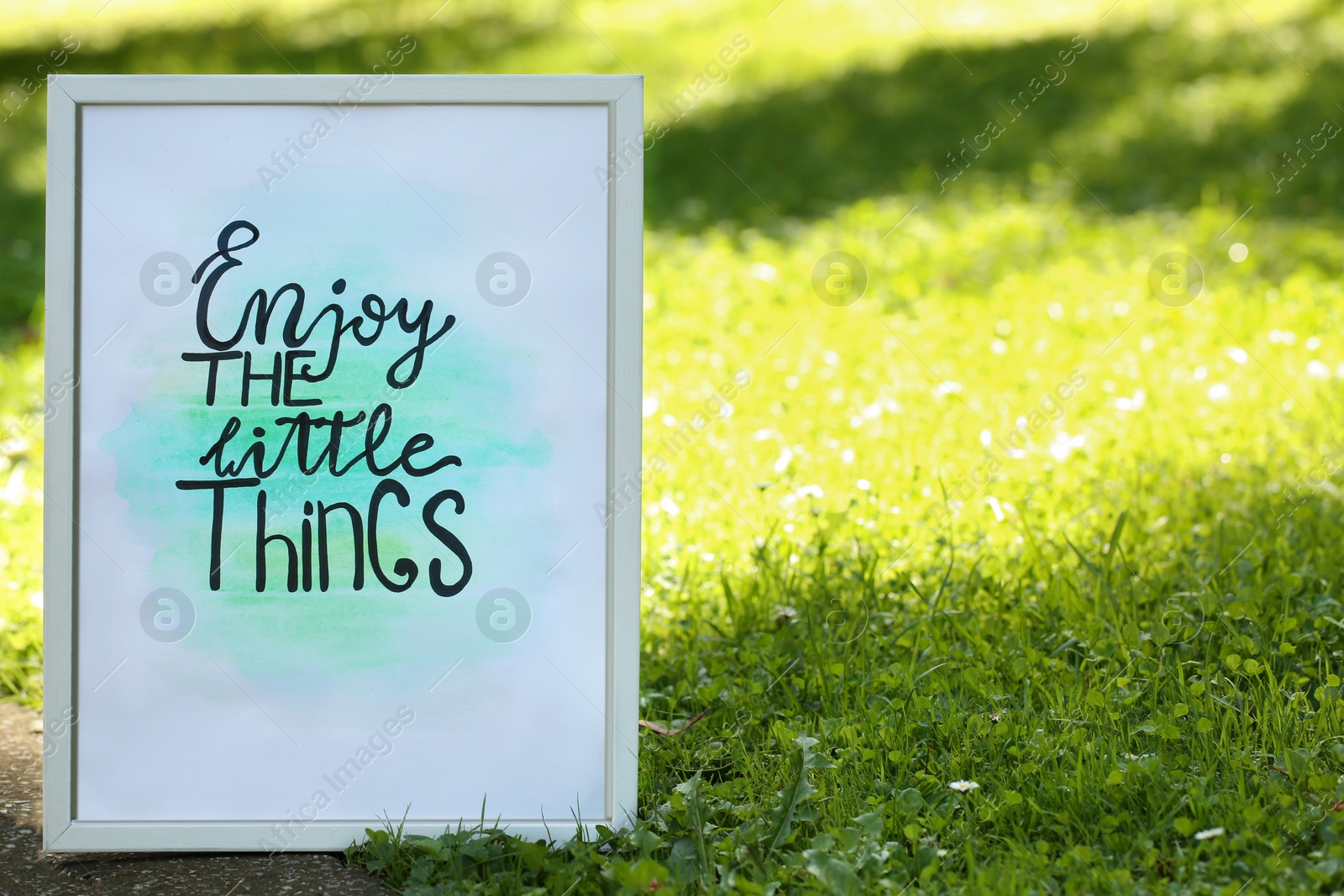 Photo of Poster with phrase Enjoy The Little Things on grass outdoors, space for text